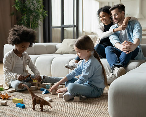 A picture of a family with parents and two children sitting in a loungeroom