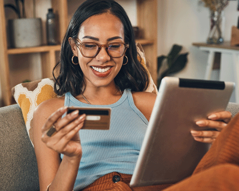 Lady on the lounge using her tablet and paying for something with her card.